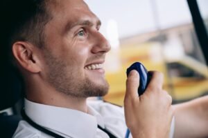 Friendly paramedic communicating via radio inside emergency vehicle. Professional healthcare setting.
