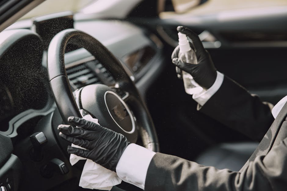 A person in gloves disinfecting a car steering wheel for hygiene and safety.