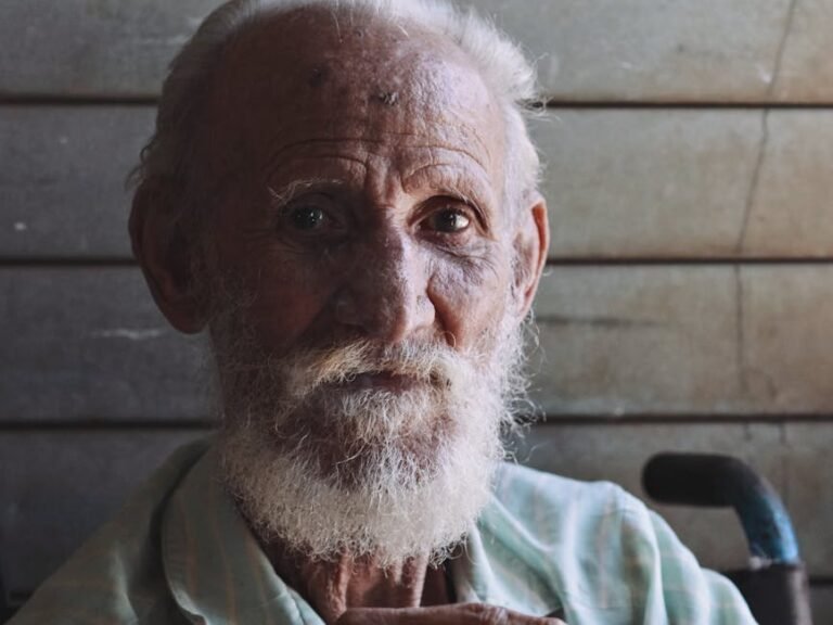 Close-up portrait of an elderly man with a white beard, looking serious and contemplative.