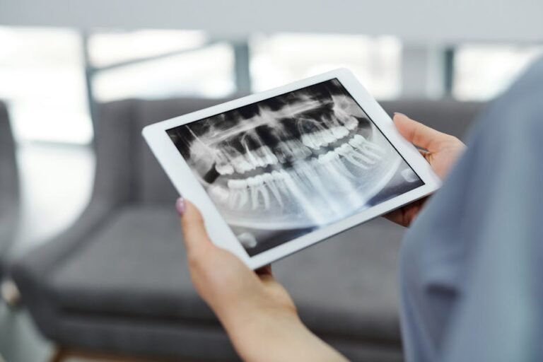Close-up of hands holding a tablet displaying a dental X-ray indoors.