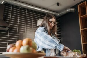 Woman in casual plaid shirt preparing food with fresh ingredients in modern kitchen.