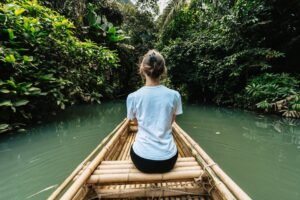 Woman on bamboo boat navigating through Krabi's lush canals, Thailand.
