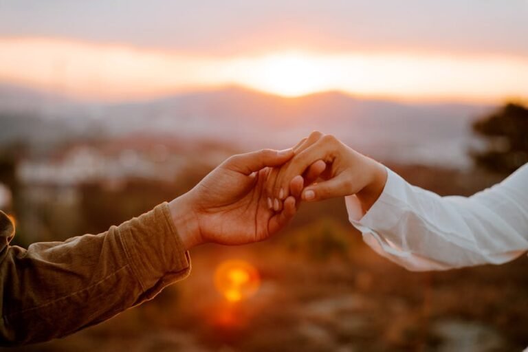 A couple shares a tender moment, holding hands during a beautiful sunset in the countryside.