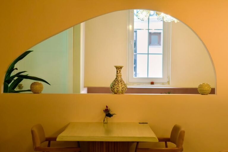 Stylish modern interior featuring an archway, decorative vase, and cozy seating area.