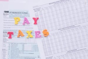 Close-up of U.S. tax forms with colorful 'PAY TAXES' letters emphasizing financial deadlines.
