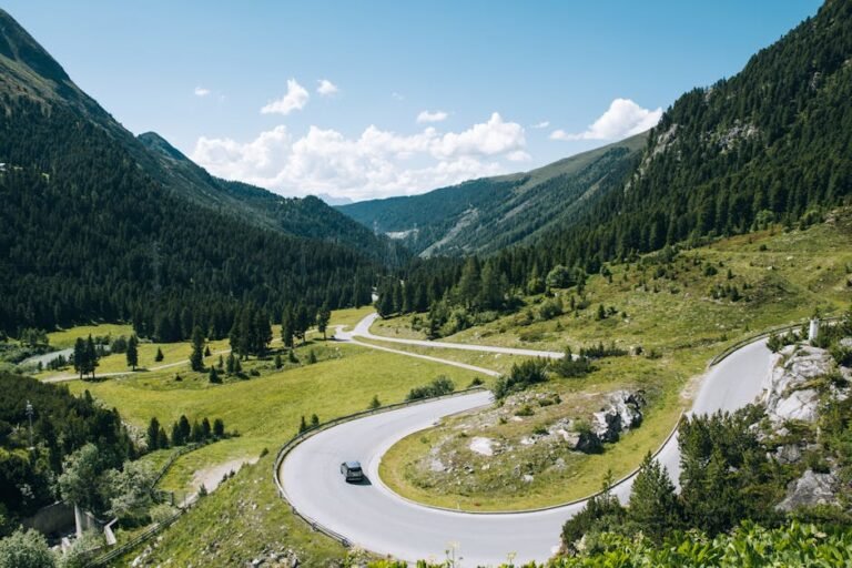 A captivating scenic view of a winding road through the lush green mountains and valleys of Tyrol, Austria.