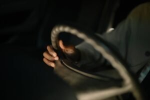 A close-up image of a hand gripping a car steering wheel, highlighting the focus on driving.