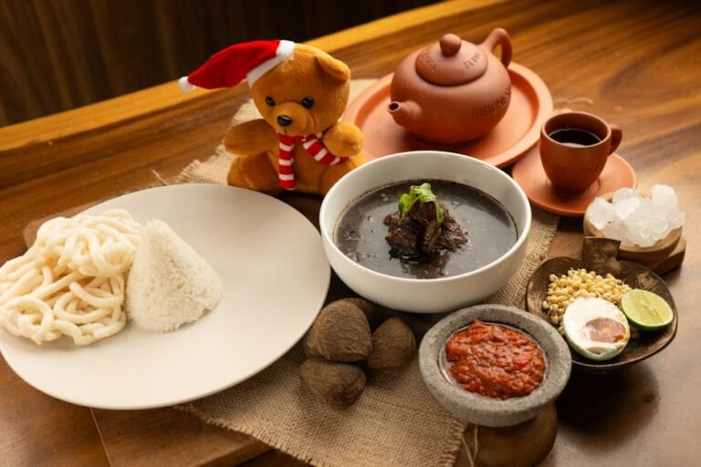 Delicious Indonesian meal featuring brongkos, rice, sambal, and hot tea with a festive teddy bear.