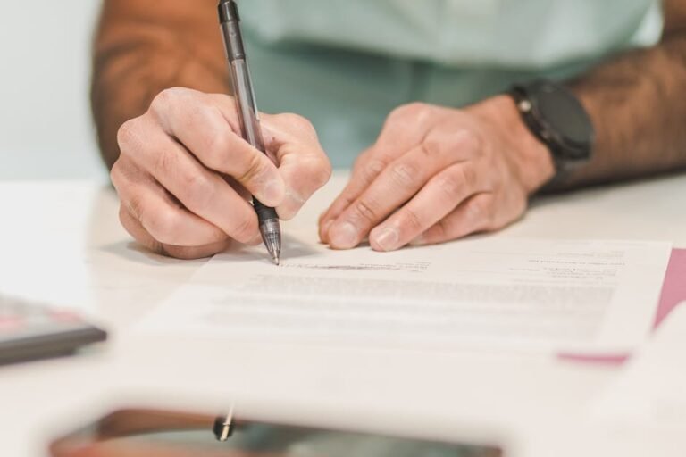 Close-up of a man signing an official document with a ballpoint pen on a desk.